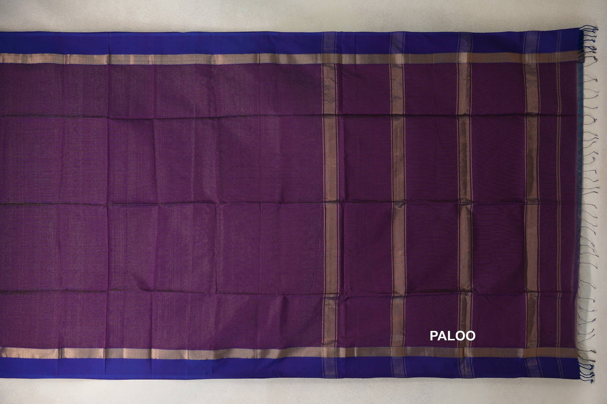 Maheshwari silk cotton saree laid flat, with a deep purple body, violet purple borders, and a striped pallu with tassels at the right edge.