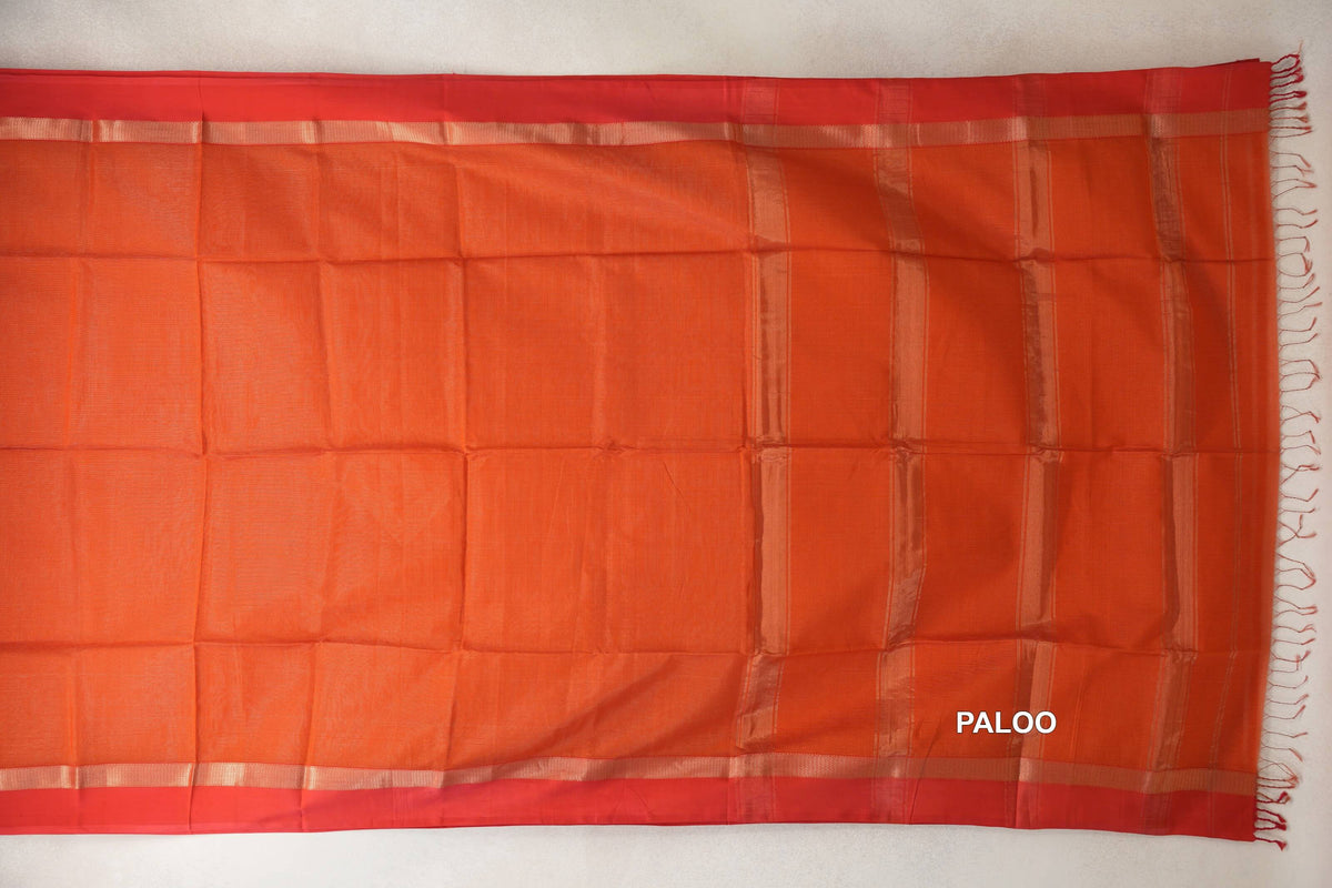 Maheshwari silk cotton saree laid flat, with a rust orange body, red borders with pale gold stripes, and a striped pallu with tassels.