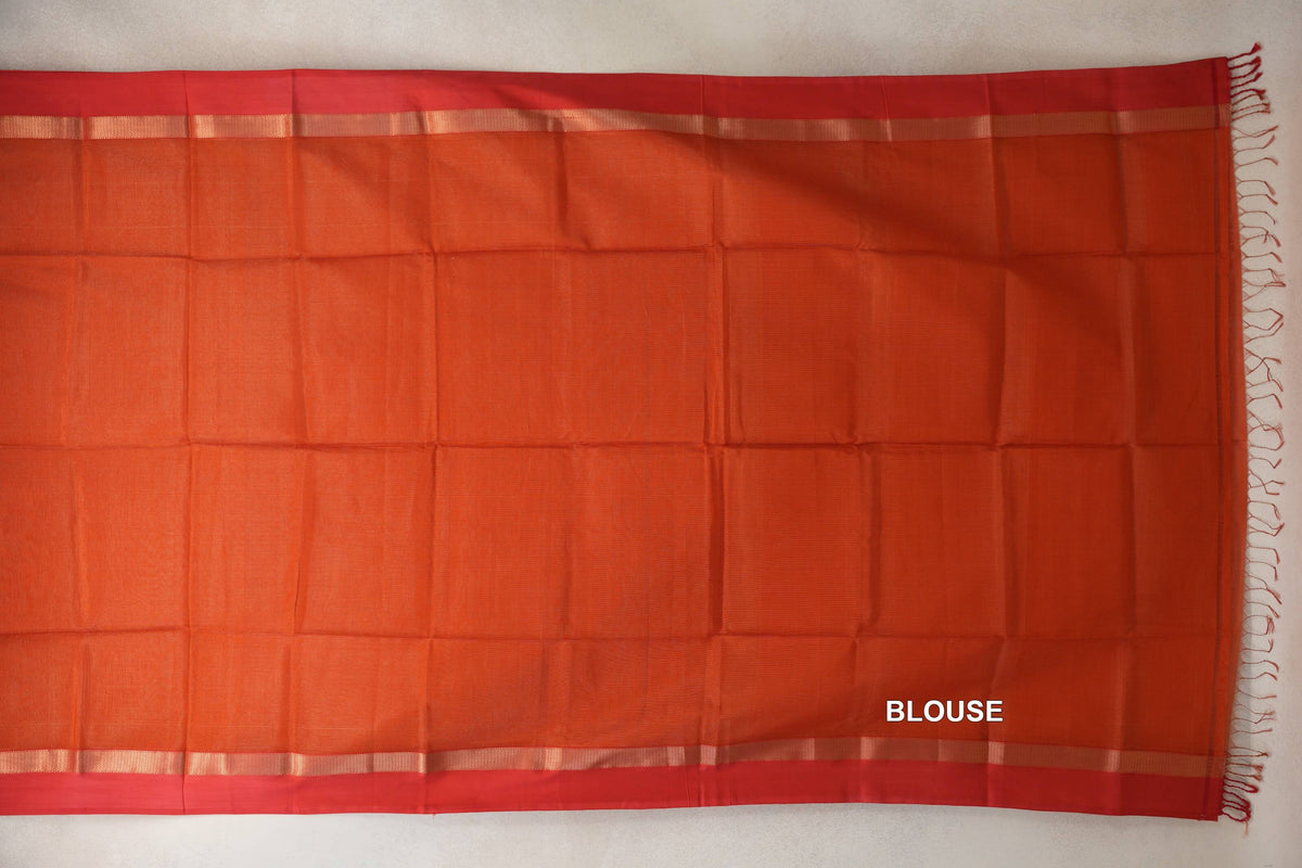 Rust orange Maheshwari silk cotton blouse piece laid flat, with red borders, narrow lustrous stripes and tassels along one edge.