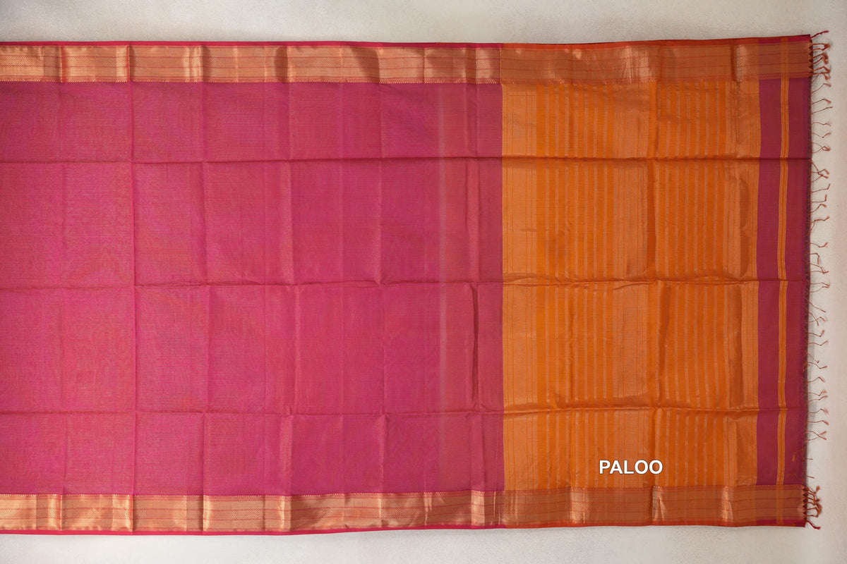 Maheshwari silk cotton saree laid flat, showing a rani pink body, gold-toned striped borders and an orange pallu with fine stripes and tassels.