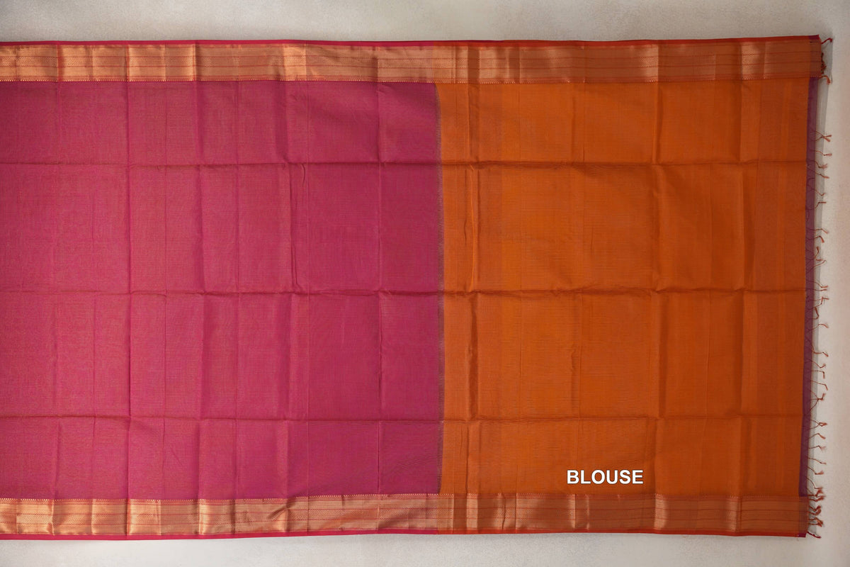 Laid-flat Maheshwari silk cotton saree with a rani pink body, orange blouse piece, striped borders and tassels along the right edge.