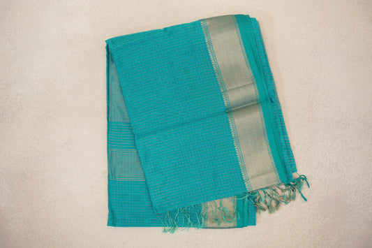 Folded turquoise green Maheshwari silk cotton saree with fine gold checks, a wide woven border and tassels at the end.