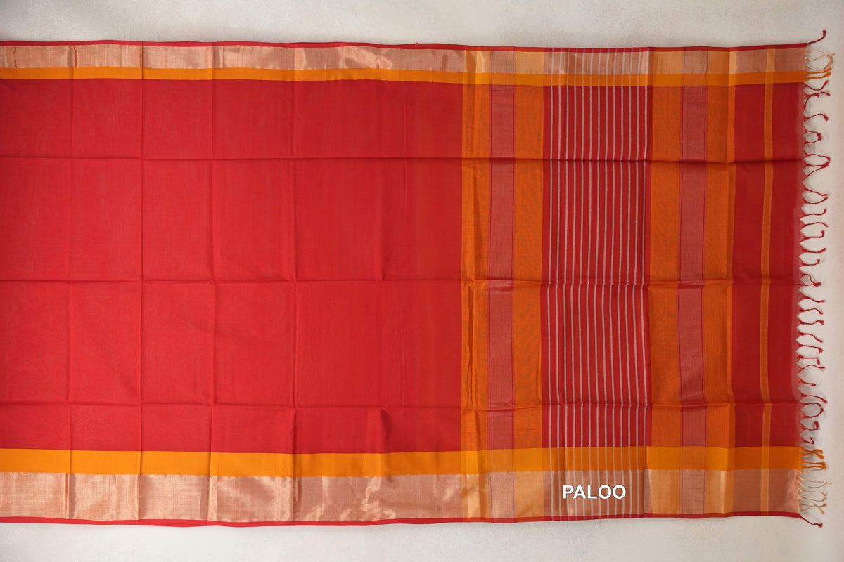 Maheshwari silk cotton saree spread flat, showing a plain tomato red body, deep orange borders and a striped red pallu with tassels.