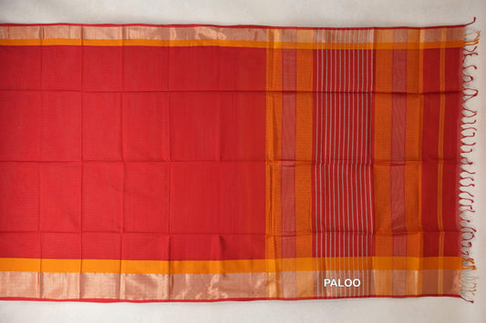 Maheshwari silk cotton saree spread flat, showing a plain tomato red body, deep orange borders and a striped red pallu with tassels.