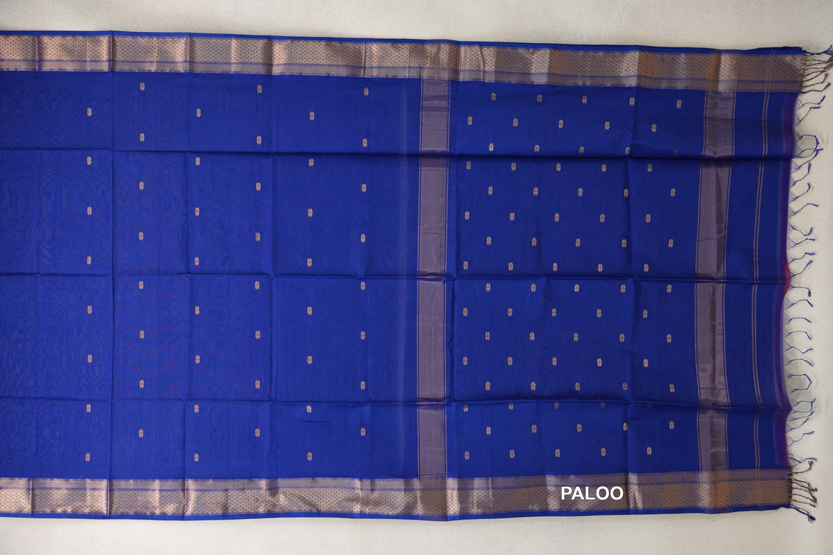 Bright royal blue Maheshwari silk cotton saree spread out, with small repeating motifs, shimmering woven borders and a tasseled pallu at right.