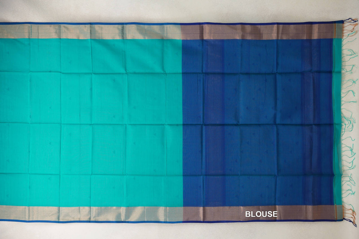 Maheshwari silk cotton saree spread flat, showing a bright turquoise green body, pale borders with blue edging, and a Classic Blue blouse section with tassels.