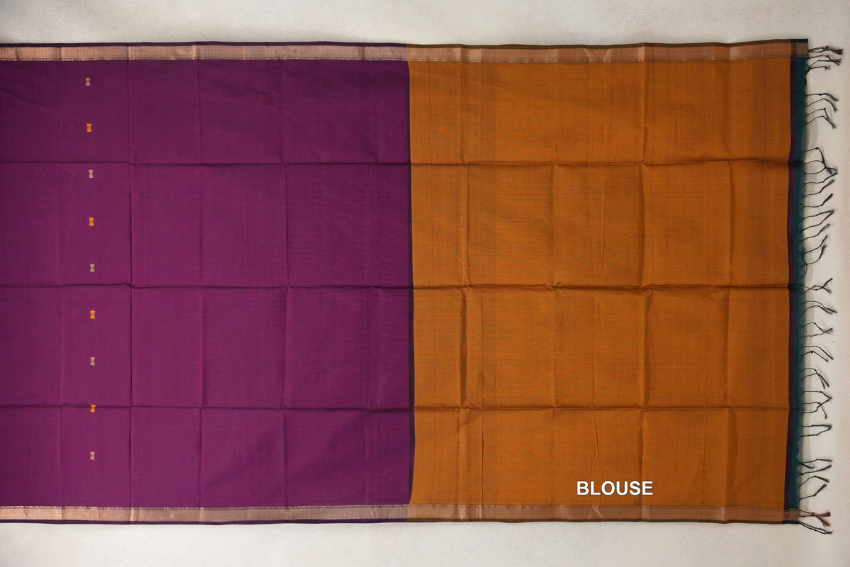 Maheshwari silk cotton saree laid flat, with a deep magenta body, small gold motifs and narrow borders beside a deep mustard orange blouse section with tassels.