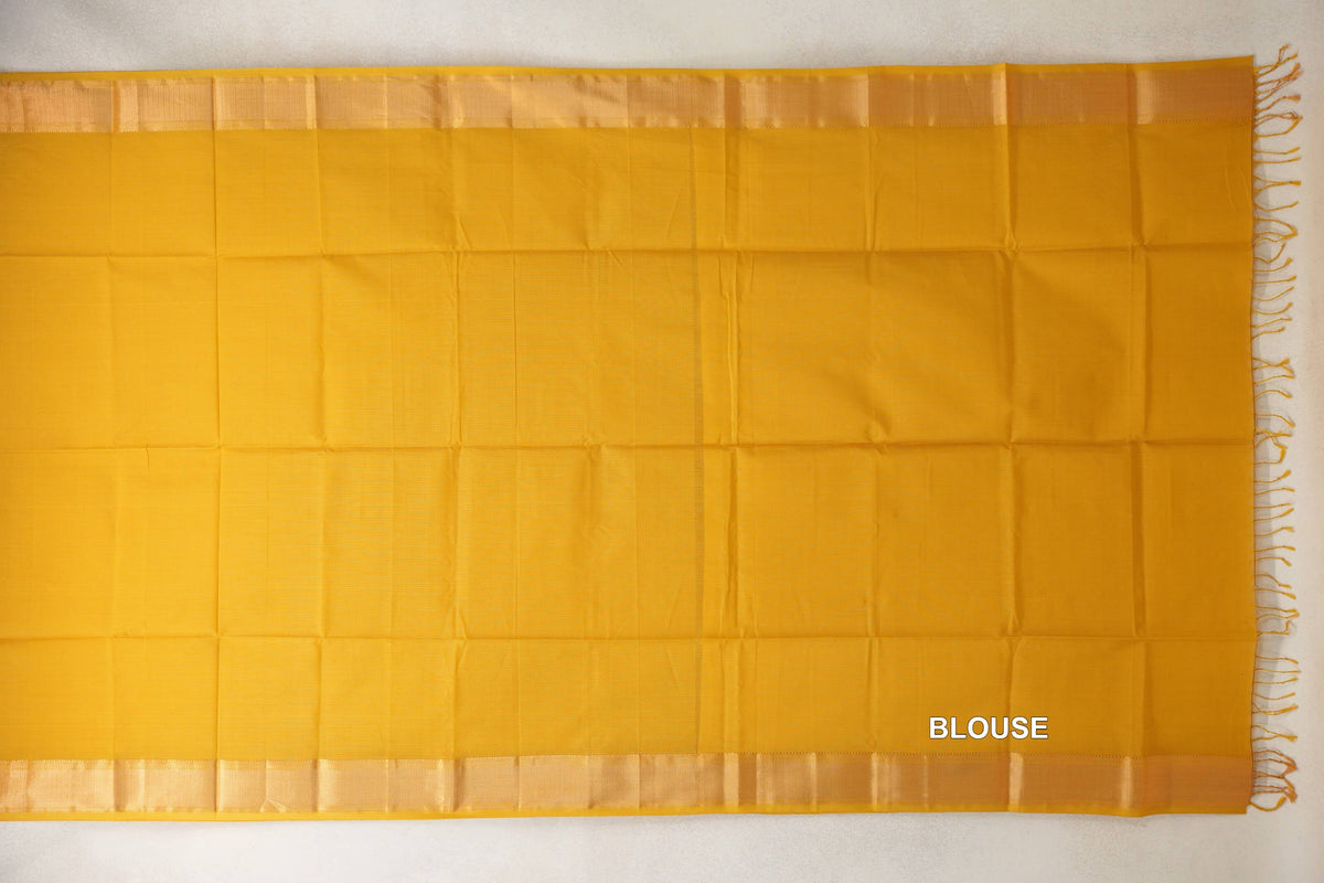 Turmeric yellow Maheshwari silk cotton blouse fabric laid flat, with lustrous borders along the top and bottom and tassels at one end.