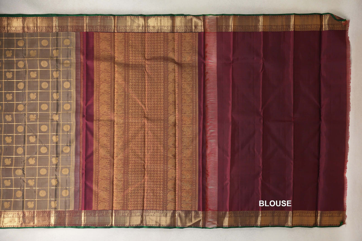 Laid-flat Kanjivaram silk saree with an olive green checked body, ornate deep maroon pallu, matching blouse and gold borders edged in bottle green.