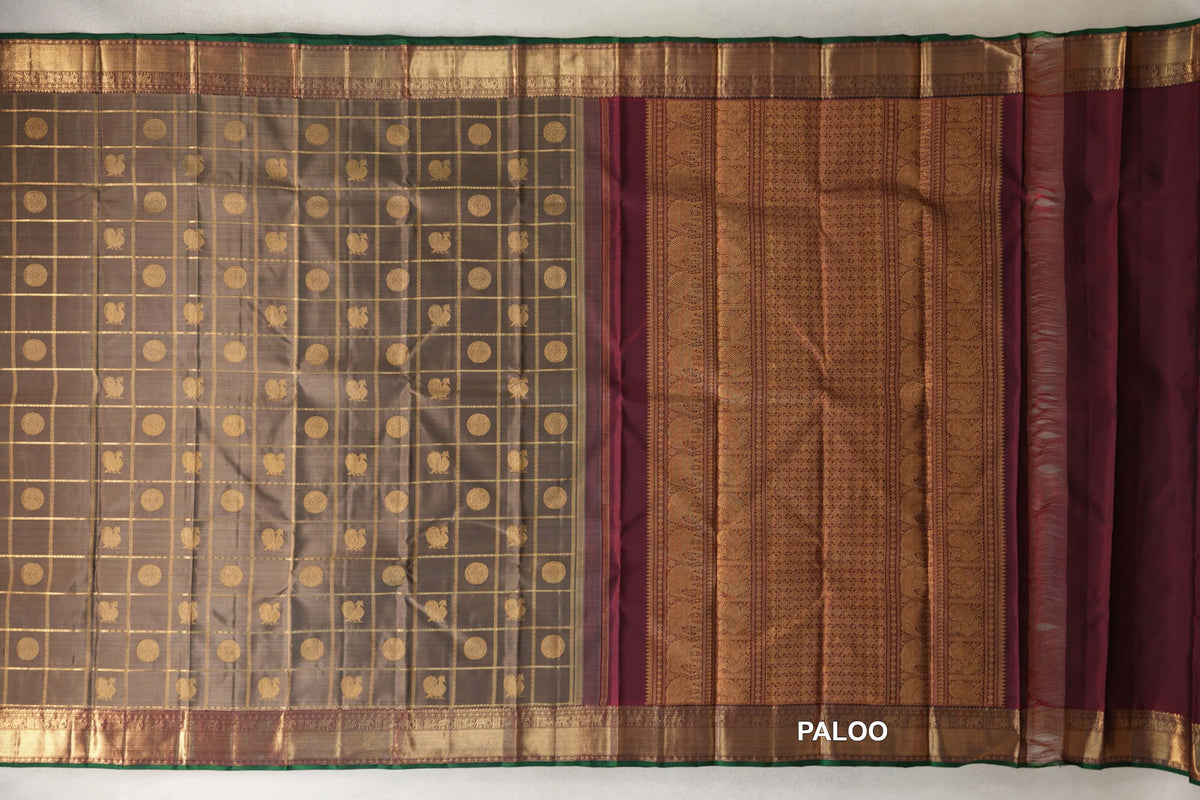 Laid-out olive green Kanjivaram silk saree with gold checks and round motifs, a patterned deep maroon pallu, gold borders and bottle green selvedge.