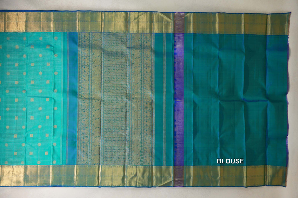 Aqua green heirloom Kanjivaram silk saree laid flat, showing a dotted body, patterned pallu, gold-toned borders and a plain blouse piece.