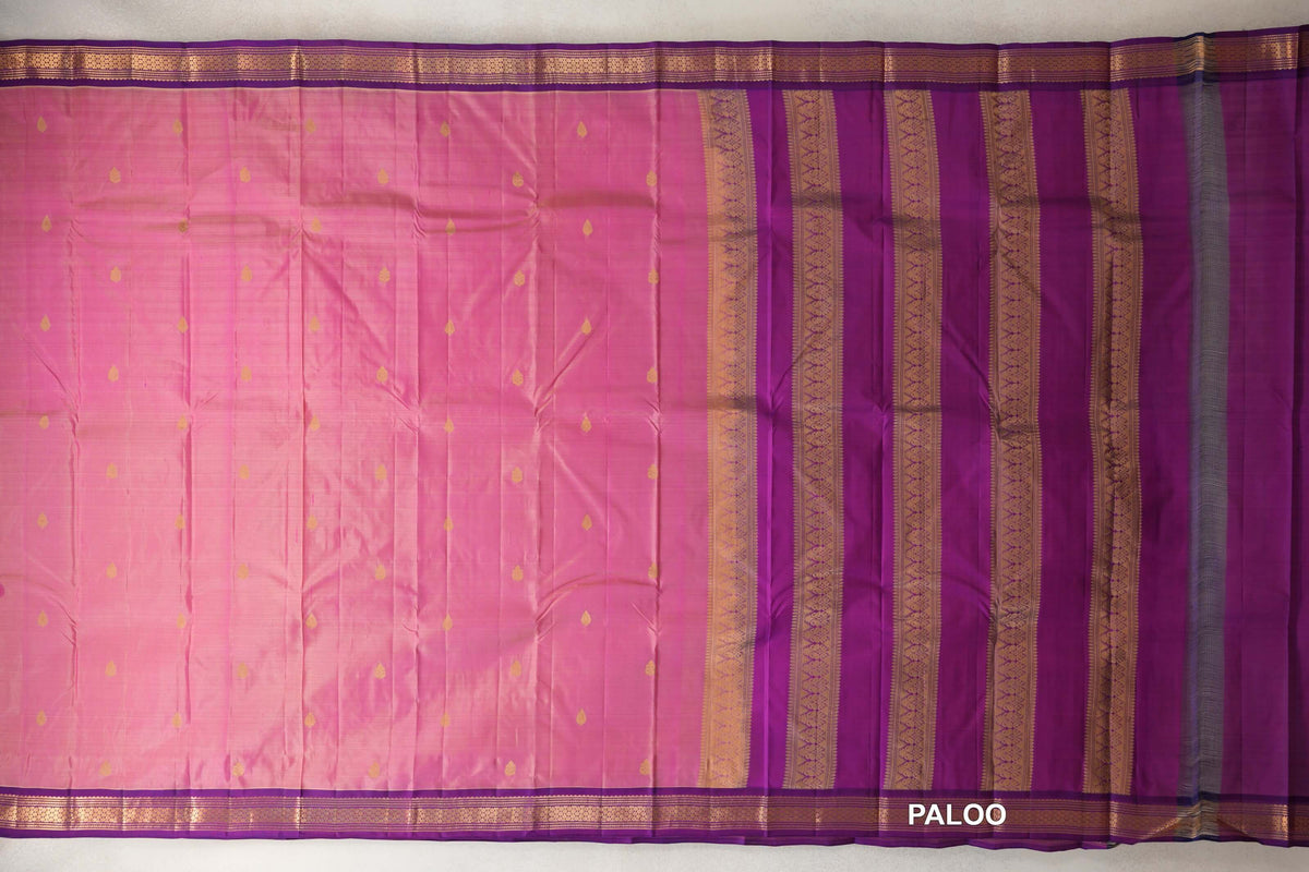 Rose pink Kanchipuram silk saree laid flat, with small gold motifs, purple borders and a purple pallu with gold patterned stripes.