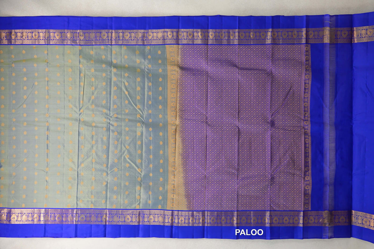 Spread-out light weight Kanchipuram silk saree with a yellowish green body, gold dots, royal blue patterned borders and a lattice-patterned pallu.