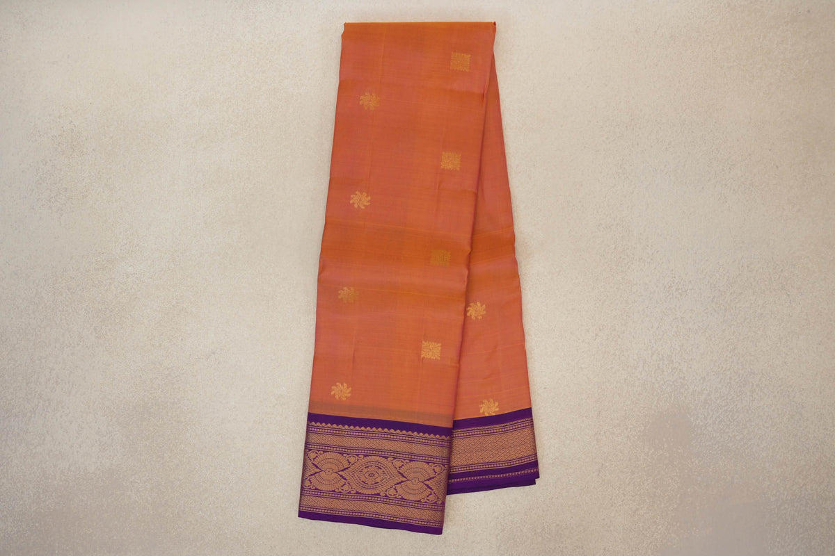 Folded light weight Kanchipuram silk saree in pink and yellow, with scattered gold-coloured motifs and a patterned deep purple border.