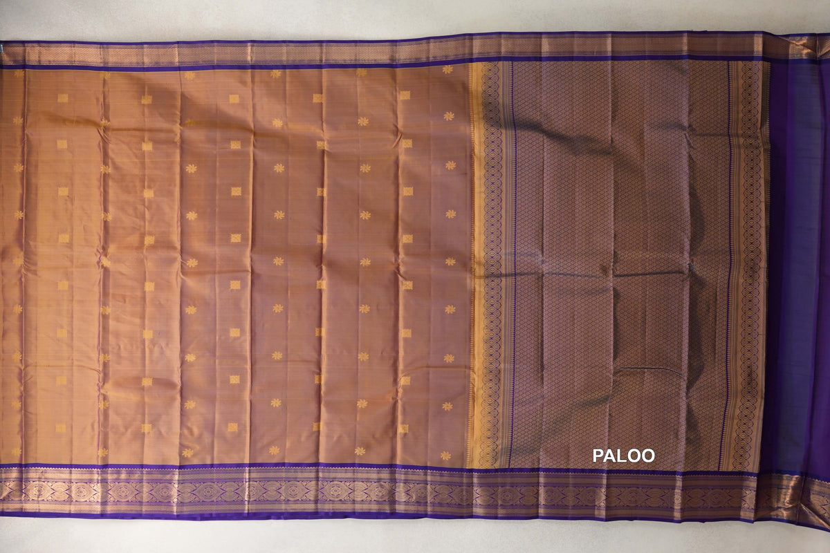 Light weight Kanchipuram silk saree spread out, showing a magenta and yellow body with small gold motifs, violet purple borders and a patterned pallu.