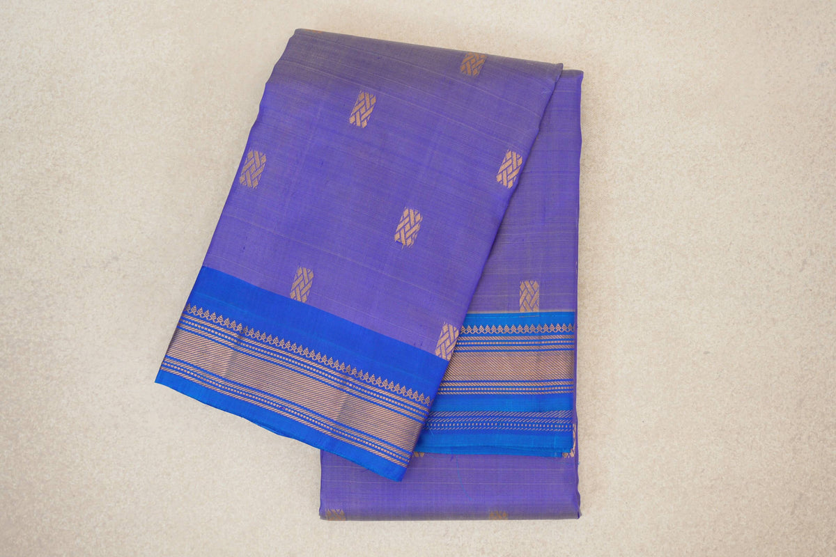 Folded lavender Kanchipuram silk saree with small gold geometric motifs and royal blue borders patterned with gold stripes.