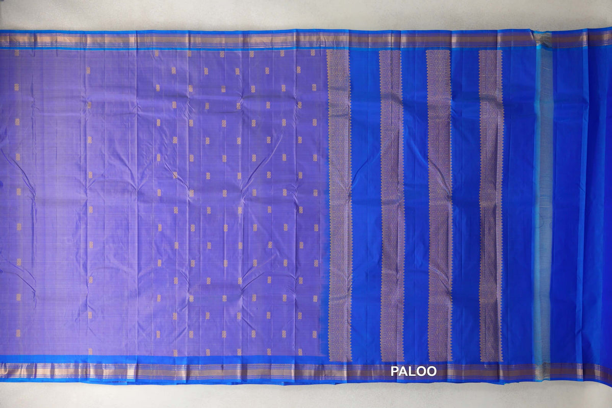 Spread-out lightweight Kanchipuram silk saree with small gold motifs on a lavender body, royal blue borders and a pallu with patterned vertical bands.