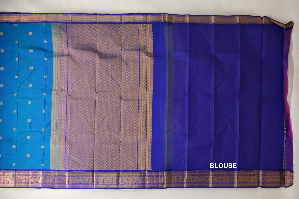 Light Weight Kanchipuram silk saree spread out, showing a peacock blue body with small gold motifs, a lattice-patterned pallu and a deep royal blue blouse piece.