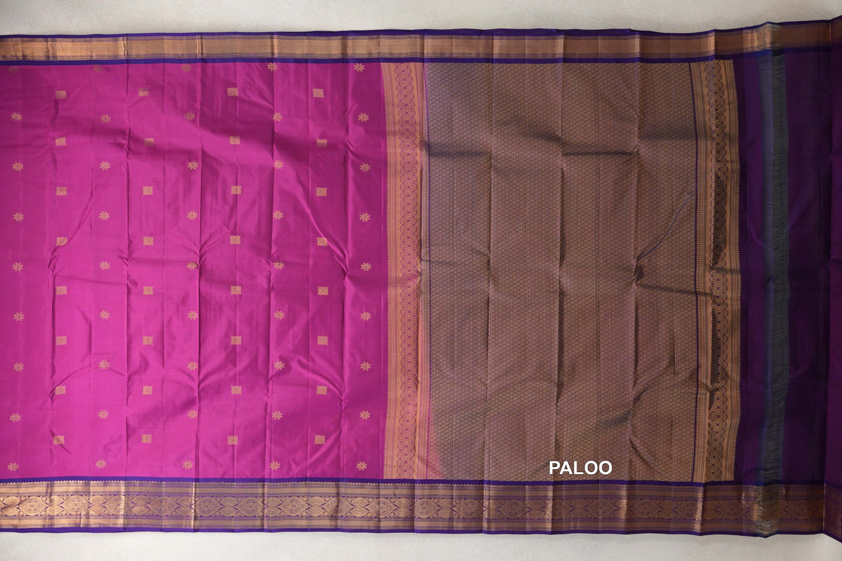Deep magenta lightweight Kanchipuram silk saree laid flat, with small gold motifs, violet purple borders and a patterned pallu.