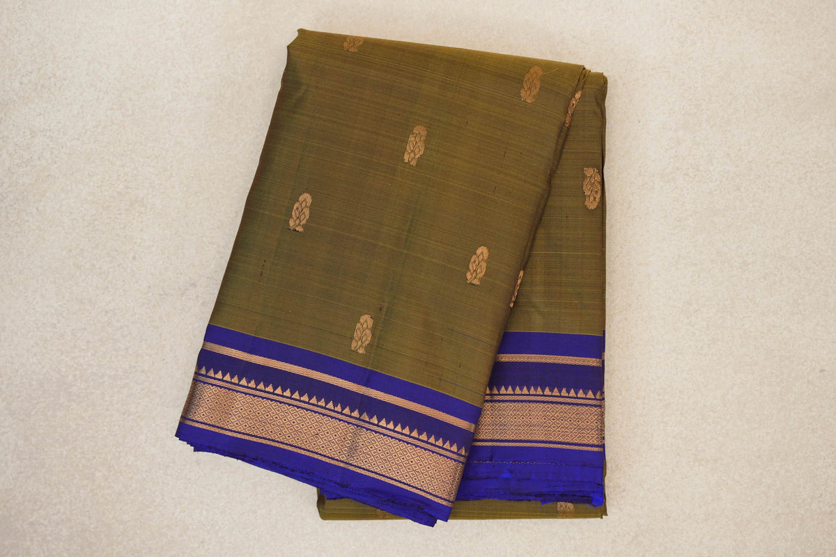 Folded lightweight Kanchipuram silk saree with an olive green body, small gold motifs and a deep royal blue border with gold geometric detailing.