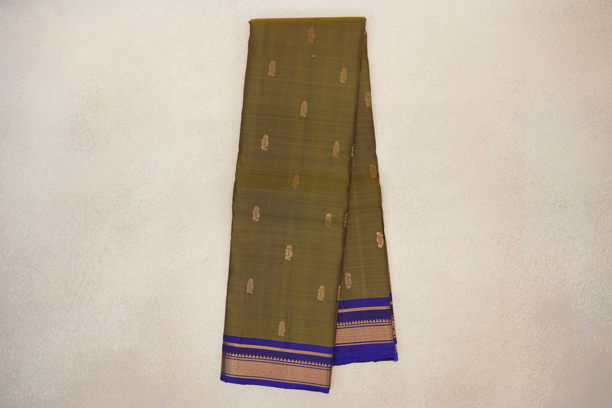 Folded light weight Kanchipuram silk saree with an olive green body, scattered gold-toned motifs and a deep royal blue border with geometric bands.