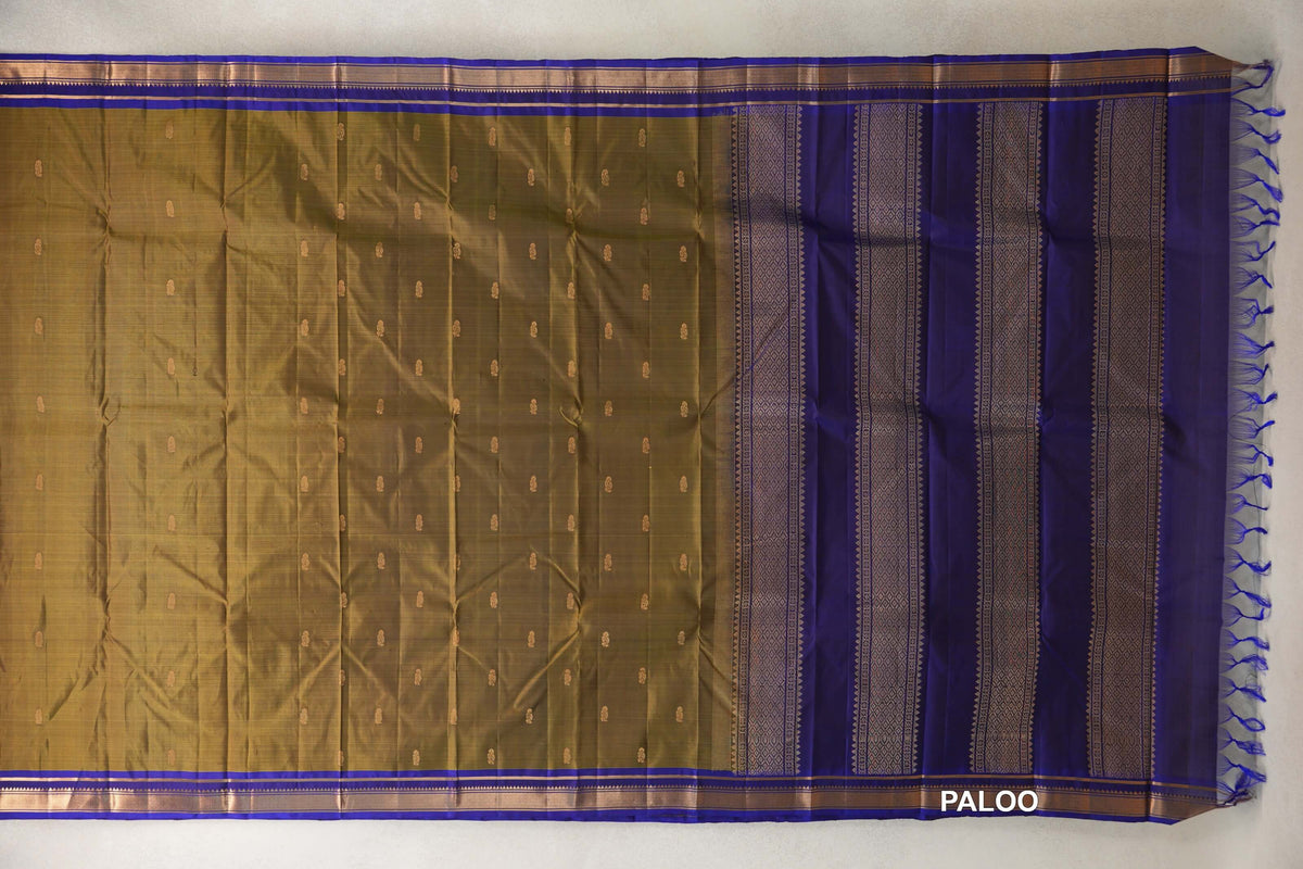 Lightweight Kanchipuram silk saree laid out with an olive green body, small gold motifs, deep royal blue borders and a patterned pallu with tassels.