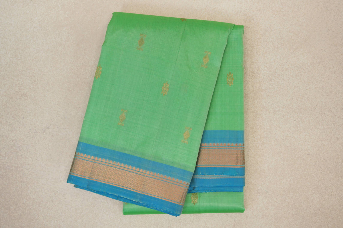 Folded mint green lightweight Kanchipuram silk saree with scattered gold-toned motifs and a light turquoise blue border with geometric detailing.