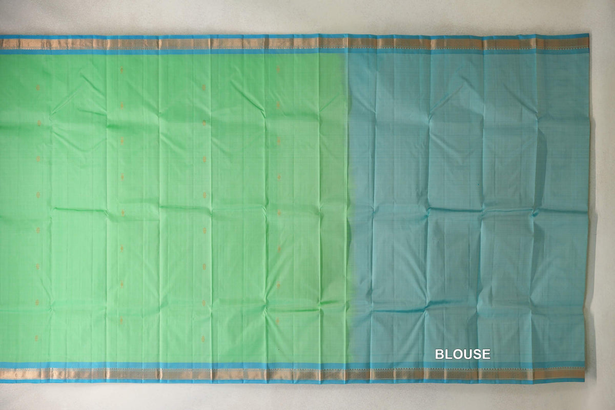 Light Weight Kanchipuram silk saree laid flat, with a mint green body dotted with small gold motifs, light turquoise blue borders and a matching blouse section at right.