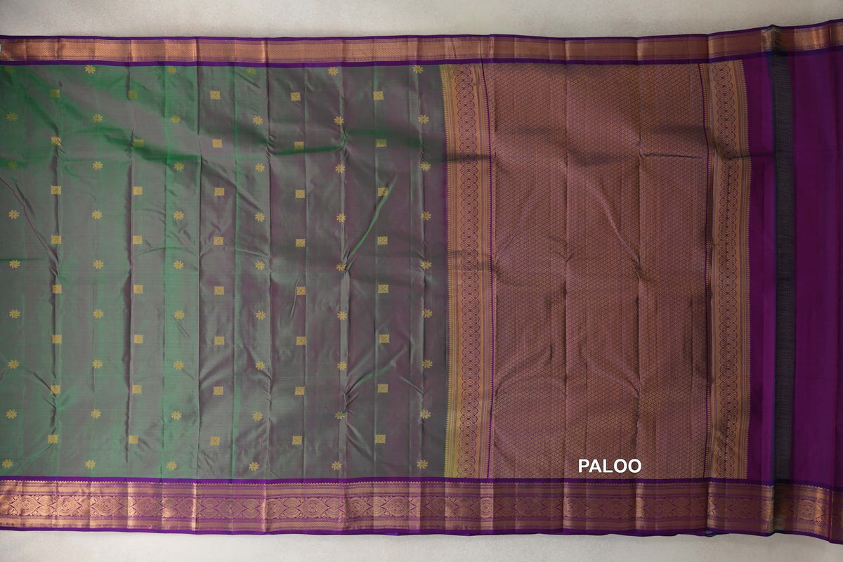 Kanchipuram silk saree laid open, showing a green and pink body with small gold motifs, violet purple patterned borders and a lattice-patterned pallu.