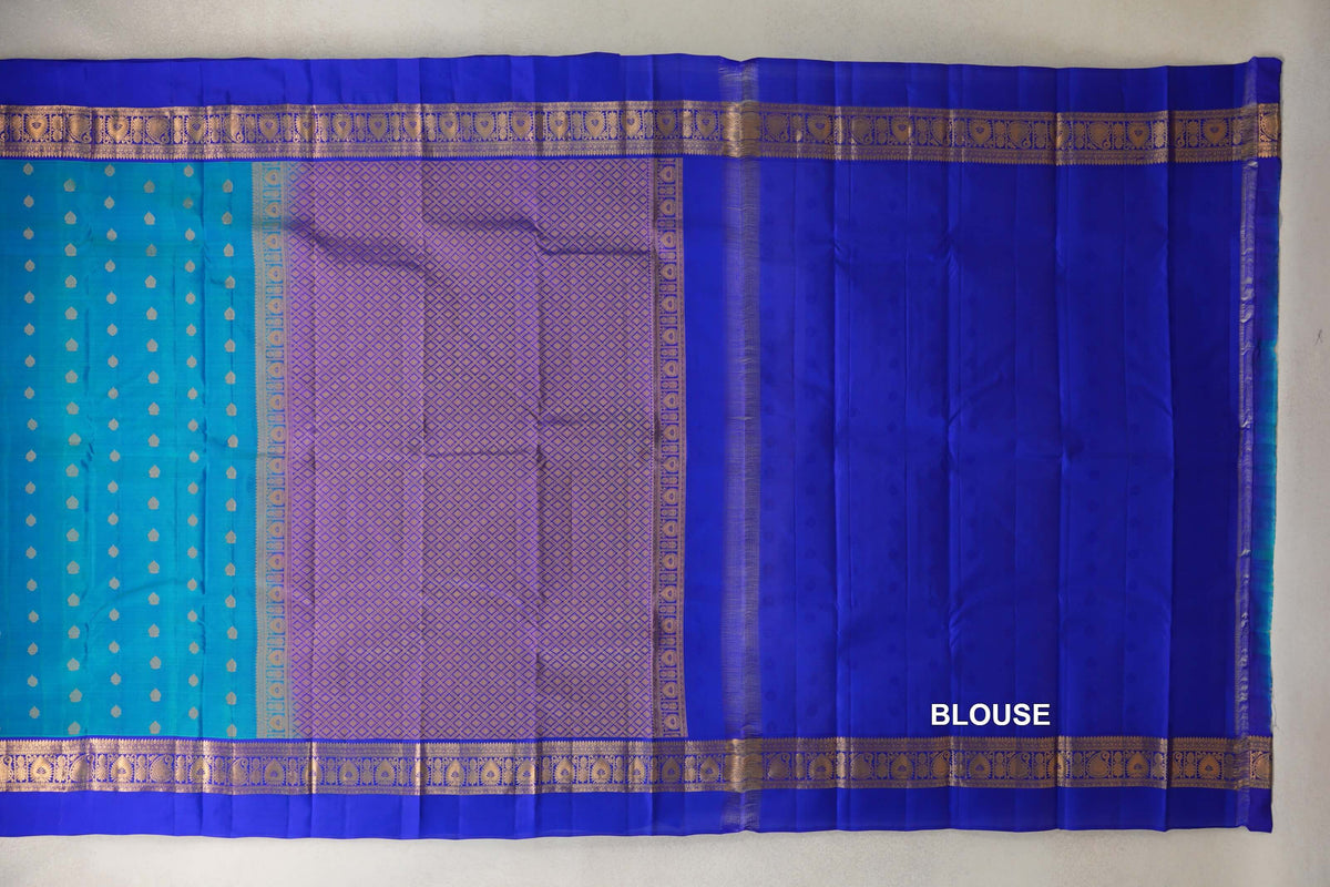 Unfolded lightweight Kanchipuram silk saree showing a peacock blue body with small gold motifs, a lattice-patterned pallu, royal blue borders and blouse fabric.