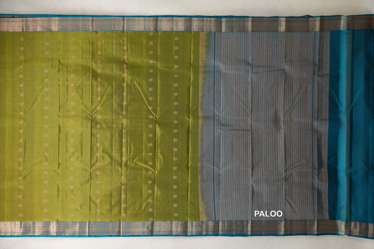 Light Weight Kanchipuram silk saree laid flat, with an olive green dotted body, a patterned teal blue pallu and silver-toned borders.