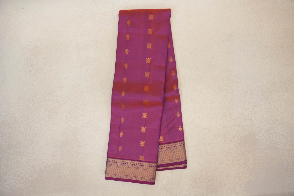 Folded blue and red lightweight Kanchipuram silk saree with scattered gold-colored motifs and a patterned gold-colored border.