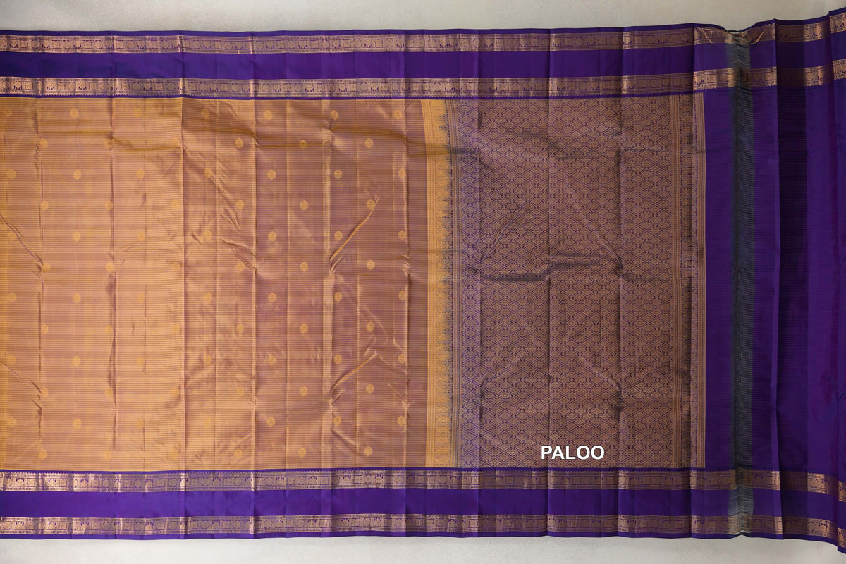 Kanchipuram silk saree spread flat, with a mustard yellow body dotted with small motifs, deep purple borders and a patterned purple pallu.