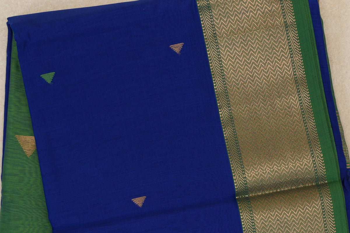 Folded Maheshwari silk cotton saree showing a royal blue body with small triangular motifs and a broad leaf green border with gold chevrons.