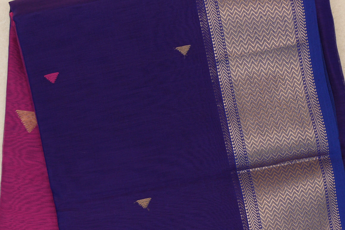 Close-up of a folded deep violet Maheshwari silk cotton saree with small triangular accents, a gold chevron border and deep rani pink fabric beneath.