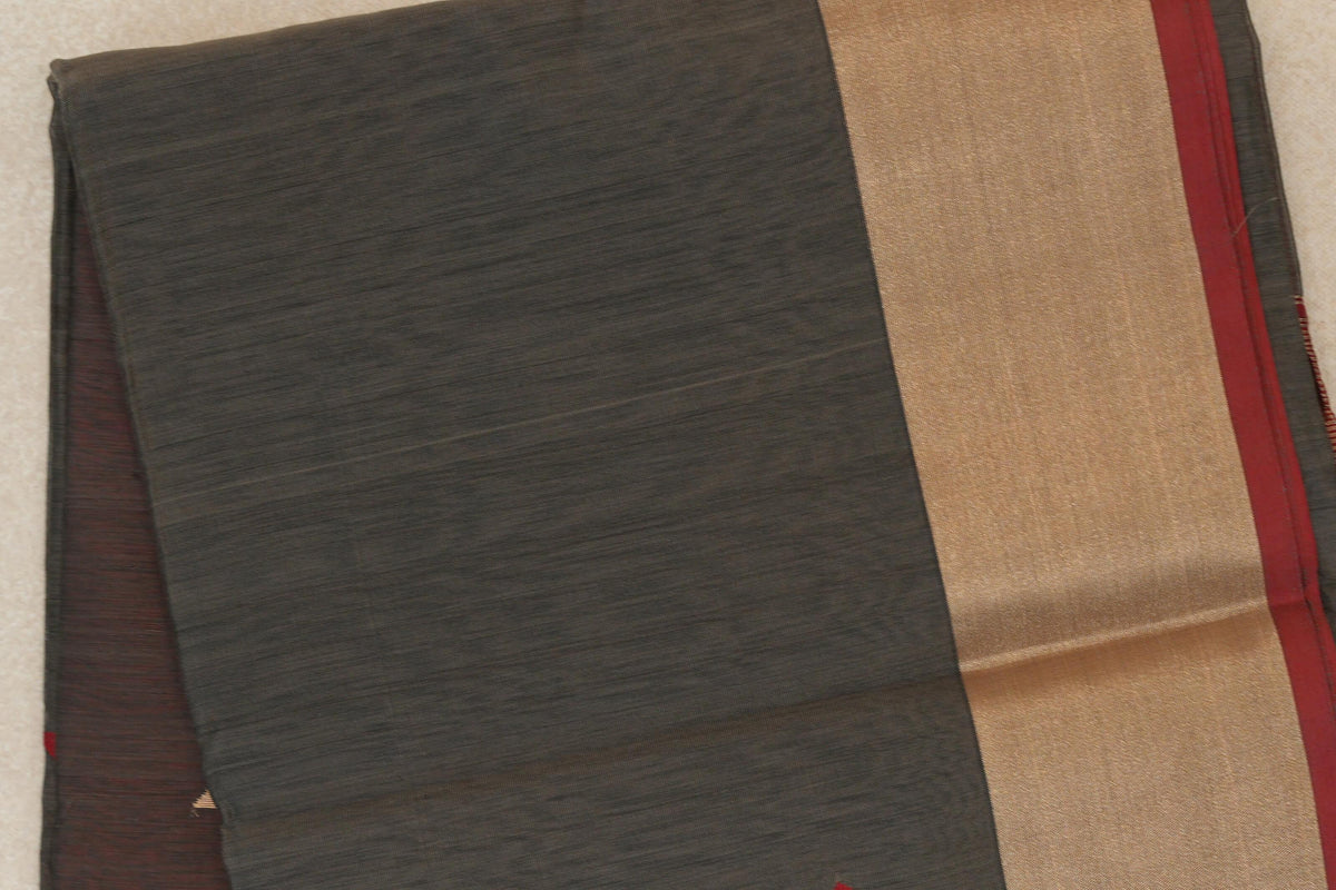 Folded Maheshwari silk cotton saree showing a charcoal grey body with fine horizontal texture, a broad gold-toned border and deep red selvedge.