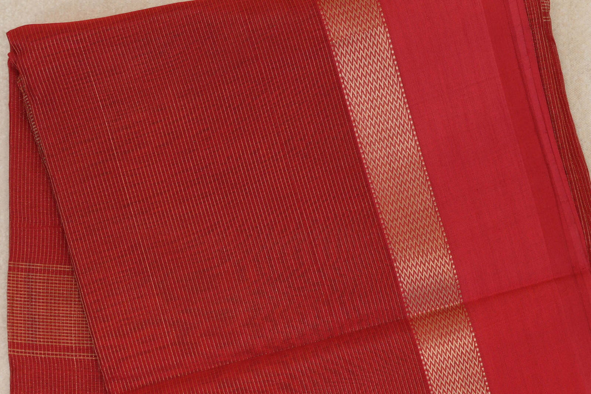 Folded Tomato Red Maheshwari silk cotton saree showing fine gold-toned stripes, a patterned border and a plain red section.