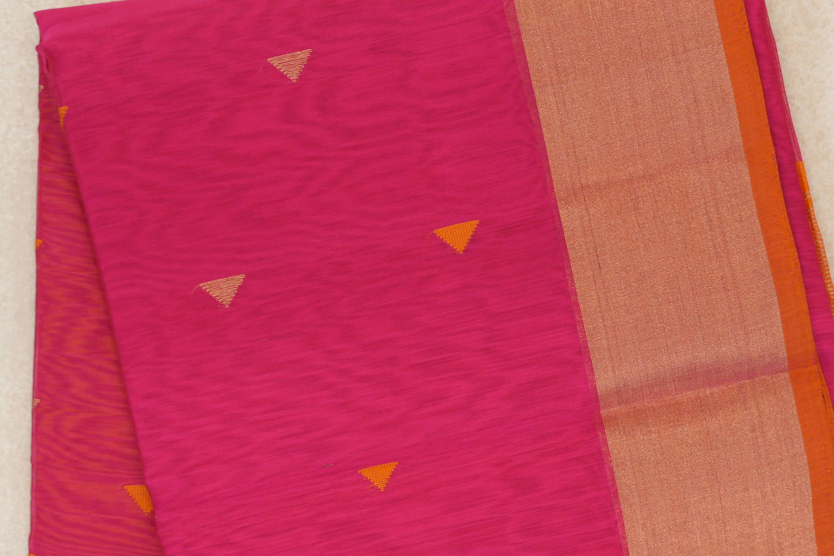 Folded Maheshwari silk cotton saree showing a Rani Pink body with small orange triangle motifs and a broad, shimmering orange border.