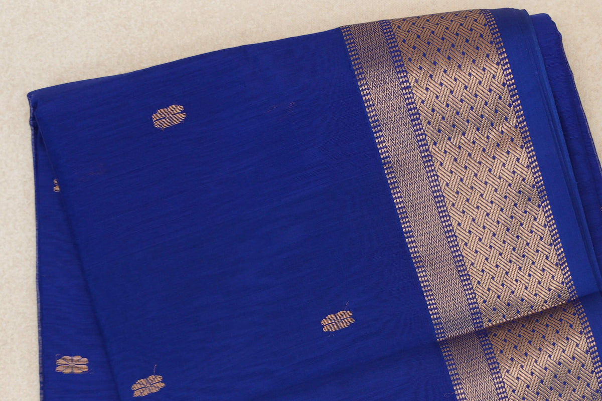 Folded bright royal blue Maheshwari silk cotton saree with small gold-toned motifs and a wide geometric border along the right edge.