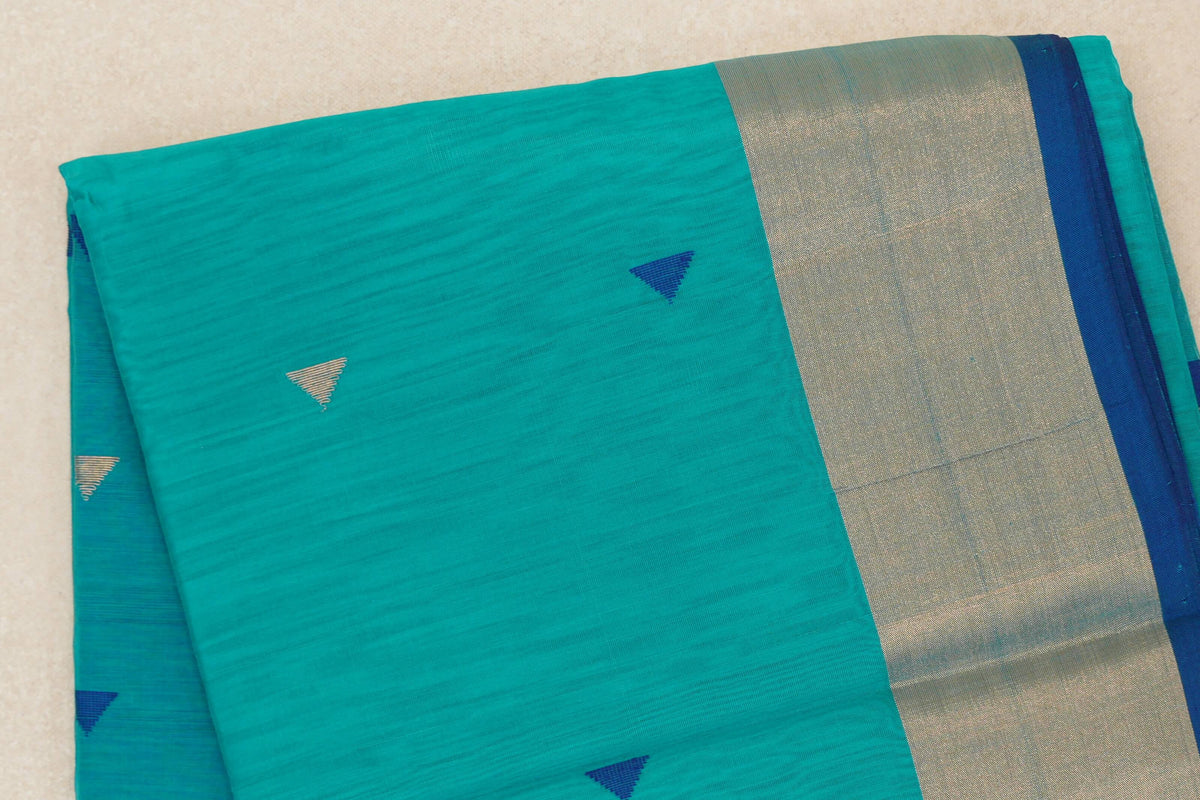 Folded Maheshwari silk cotton saree in Bright Turquoise Green, with small blue and silver triangular motifs, a broad metallic border and Classic Blue selvedge.