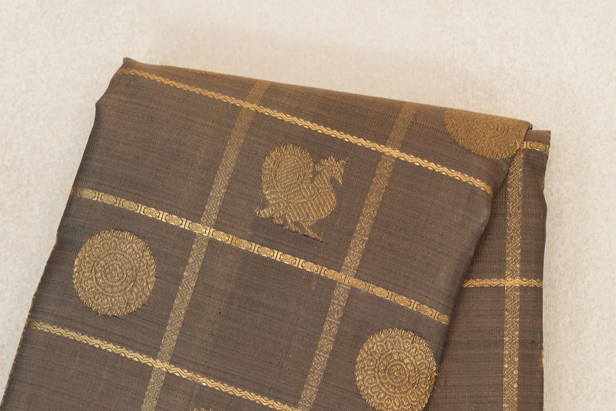 Folded olive green Kanjivaram silk saree with gold circular motifs and fine woven stripes forming a grid.