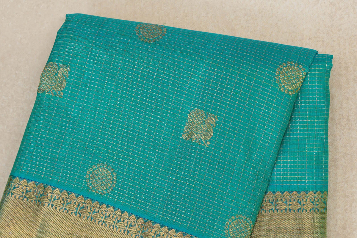Folded aqua green Kanjivaram silk saree with fine gold checks, scattered woven motifs and a broad patterned gold border.