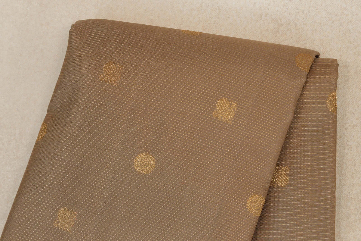 Folded greenish beige Kanjivaram silk saree with fine gold-toned stripes and scattered small woven motifs.