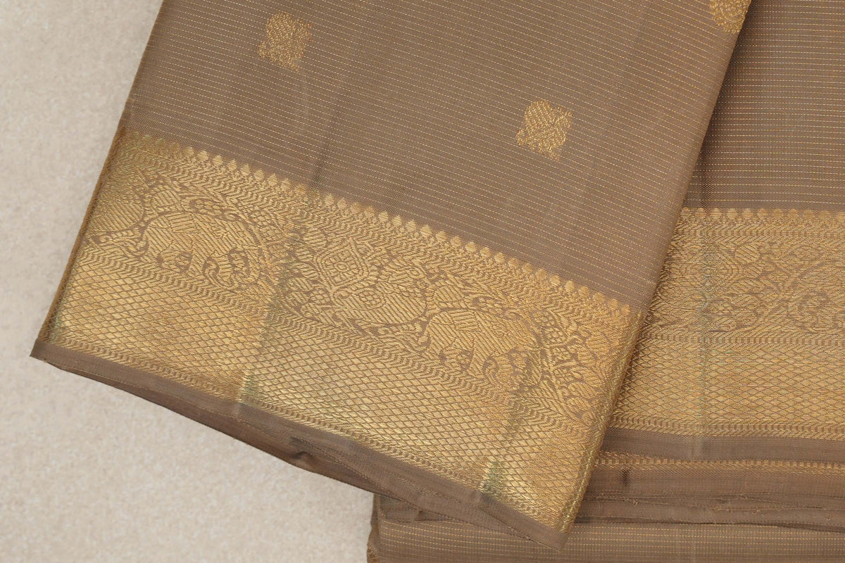 Folded greenish beige Kanjivaram silk saree showing fine stripes, small gold motifs and a broad gold border with elephant designs.
