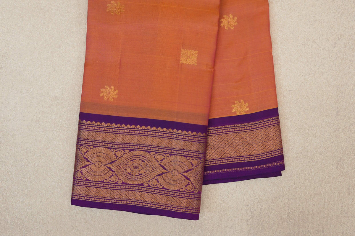 Folded light weight Kanchipuram silk saree showing a pink and yellow body with scattered gold motifs and deep purple borders with intricate gold patterns.