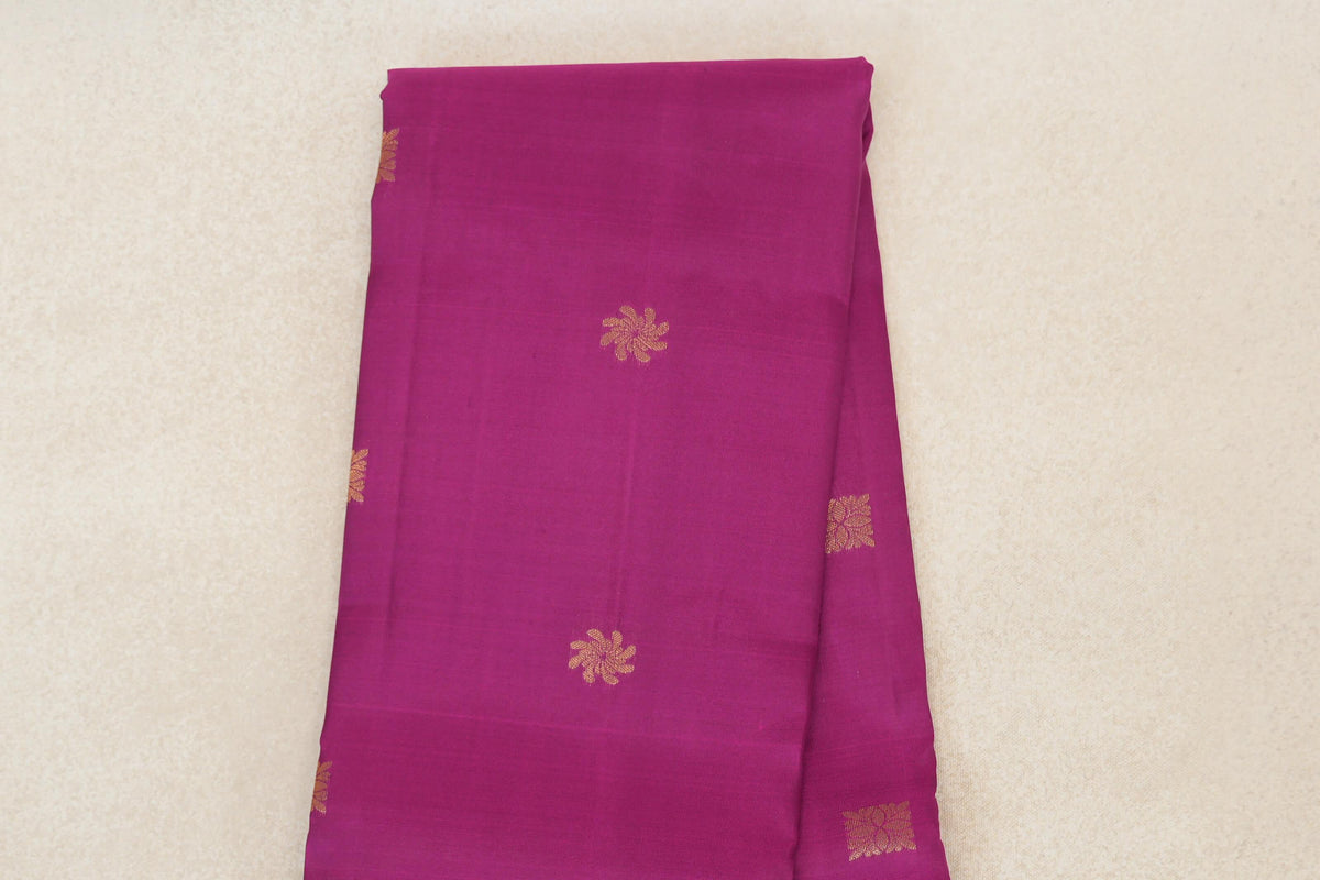 Folded deep magenta lightweight Kanchipuram silk saree showing scattered gold-toned floral motifs on the body.