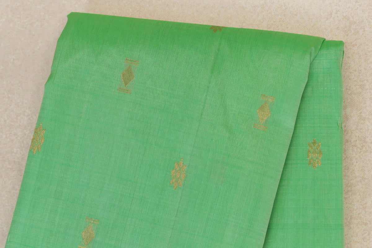 Folded mint green light weight Kanchipuram silk saree, showing the body with scattered small gold geometric motifs.