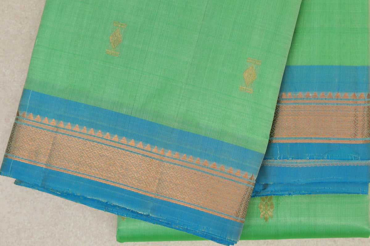 Folded mint green lightweight Kanchipuram silk saree with small gold motifs and a light turquoise blue border with gold geometric detailing.
