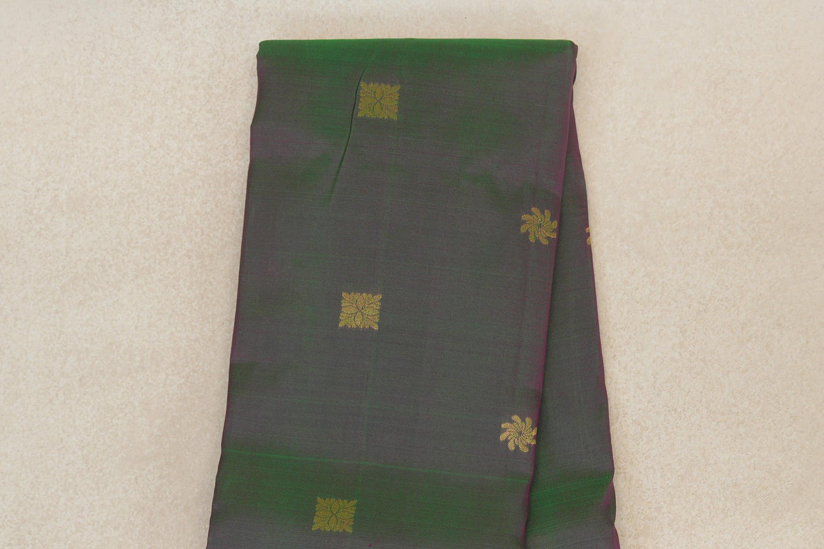 Folded light weight Kanchipuram silk saree in muted green and pink, with small gold square and floral motifs and violet purple edging.