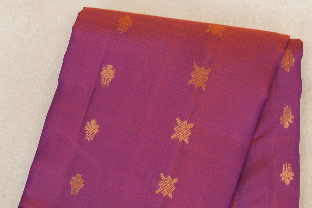 Folded blue and red Kanchipuram silk saree with a purplish hue and scattered gold-toned floral and star motifs.